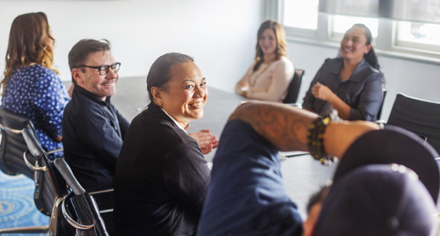 A diverse group of professionals, smiling, seated at a boardroom table